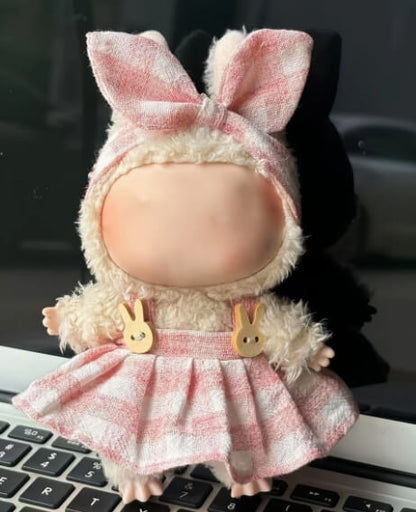 Close-up of a Labubu doll wearing Zibuya’s pink gingham dress and bow headband, showing the wooden bunny buttons, photographed indoors on a laptop keyboard.