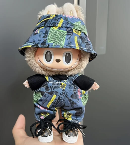 Close-up of a Labubu plush doll wearing Zibuya’s urban streetwear set, featuring a blue newspaper-print bucket hat, matching overalls, and sneakers for a trendy collectible look.