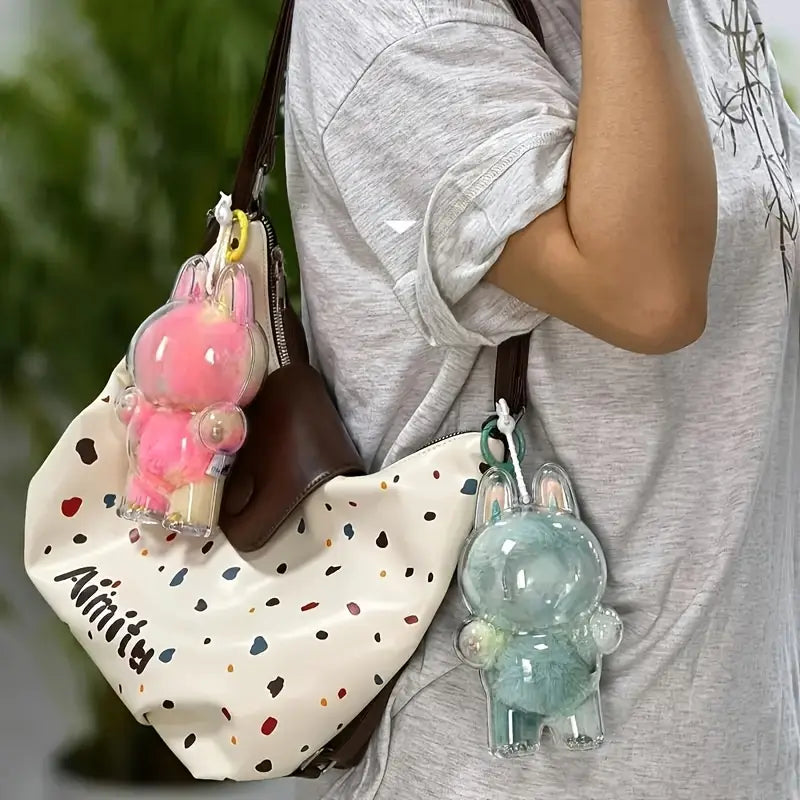  Zibuya Labubu dolls in clear acrylic protective cases, hanging on a bag as charms, featuring pink and mint fur designs for stylish, on-the-go display and protection.